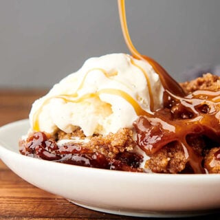 plate of apple cobbler being drizzled with caramel