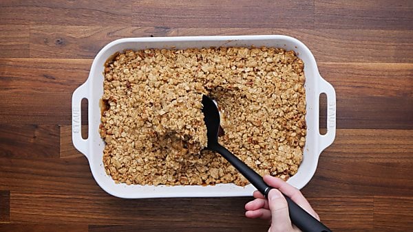 Baked apple crisp with ladle being scooped out