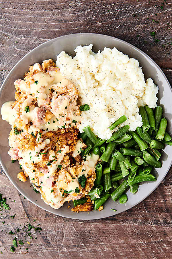 plate of crockpot chicken cordon bleu with mashed potatoes and green beans above