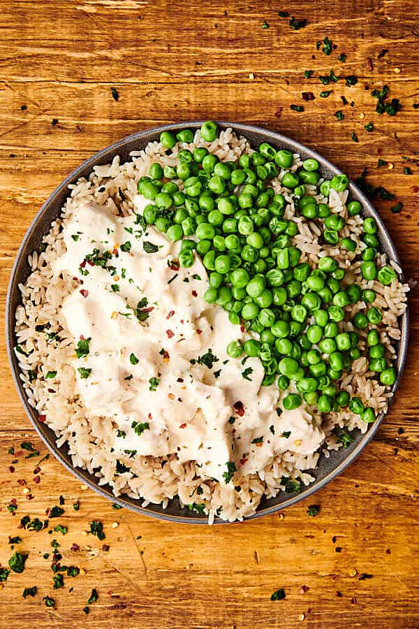 plate of ranch chicken over rice with peas above