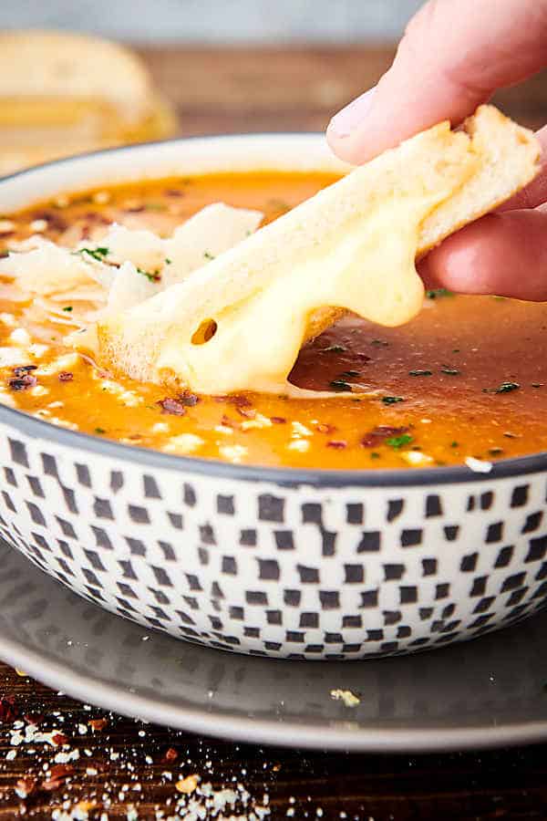 bread being dipped into bowl of tomato soup