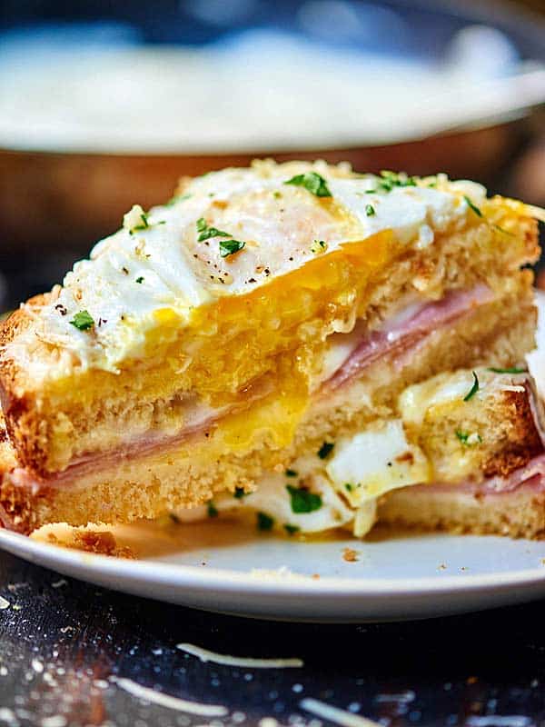 Croque Madame sandwich cut in half, one half resting on the other