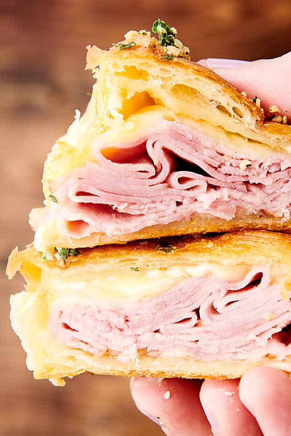 two halves of ham and cheese croissant held