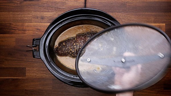 lid being taken off crockpot with ham in it