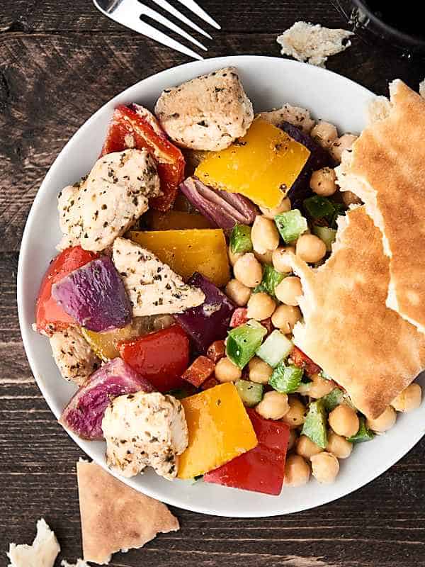 greek chicken with veggies and chickpeas on plate above