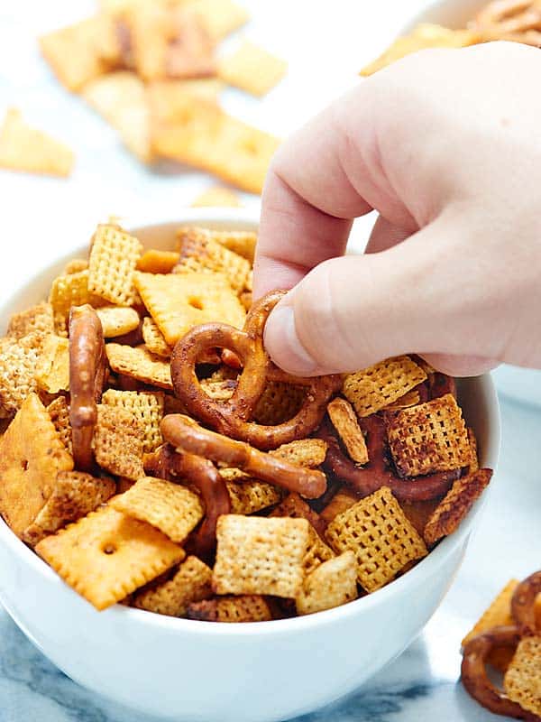pretzel being taken out of bowl of chex mix