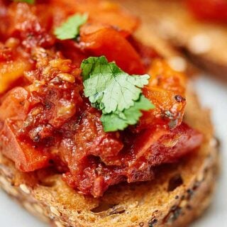 This sun dried and roma tomato bruschetta is truly flavorful and has amazing texture...I swear you won't believe it's healthy for you! I love the toasty crunch of the bread that's piled with two types of warm, juicy, tender tomatoes, spicy garlic, tangy balsamic, and sweet basil! showmetheyummy.com #bruschetta #tomato #healthy #vegan #vegetarian